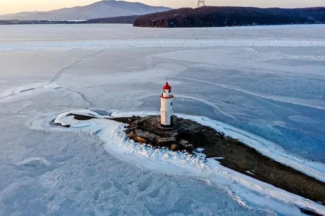 An aerial view of Tokarevsky Lighthouse which stuck between ice floes in Vladivostok, Russia, on February 01, 2022. The lighthouse was stuck in the ice after the weather conditions, which were effective up to minus 50 degrees in winter. The Tokarevsky Lighthouse, which is accepted as the last point on the land in the world and the beginning of the Pacific Ocean, has become the most important center of tourism in the region. The 11.9-meter-high lighthouse on the 800-meter-long island is one of the oldest operating lighthouses in the Russian Far East, built in 1876. (Photo by Matvei Nosarev/Anadolu Agency via Getty Images)