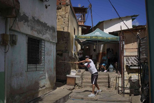 A man takes a swing while playing the traditional game of “chapitas” or Caps, in the San Agustin neighborhood of Caracas, Venezuela, Saturday, January 29, 2022. The popular game is similar to baseball and played with bottle caps in place of a ball, and a stick in place of a bat. (Photo by Matias Delacroix/AP Photo)