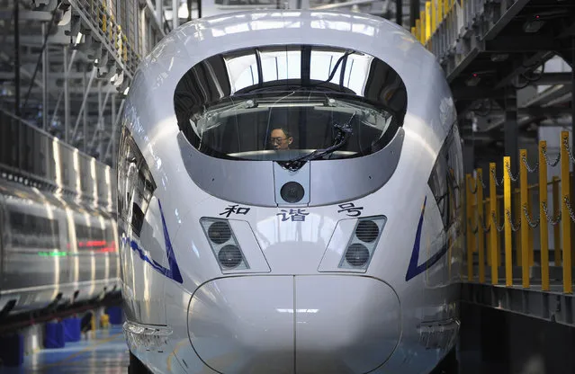 An employee adjusts a CRH380B high-speed Harmony bullet train as it stops for an examination during a test run, at a bullet train exam and repair center in Shenyang, Liaoning province Tuesday, October 23, 2012. (Photo by Reuters/Stringer)