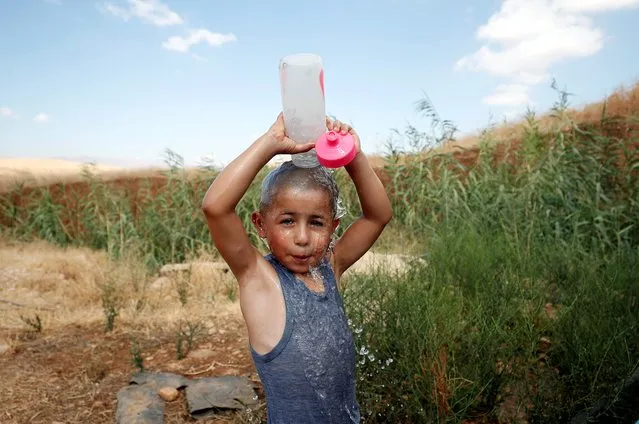 A Palestinian boy pours water onto himself to cool off in Jordan Valley in the Israeli-occupied West Bank on August 21, 2019. (Photo by Mohamad Torokman/Reuters)