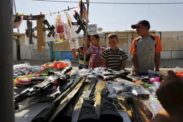 Syrian refugee children buy toys during the first day of Eid al-Fitr, marking the end of the holy month of Ramadan, the Al-Zaatari refugee camp in Mafraq, Jordan, near the border with Syria, July 17, 2015. (Photo by Muhammad Hamed/Reuters)