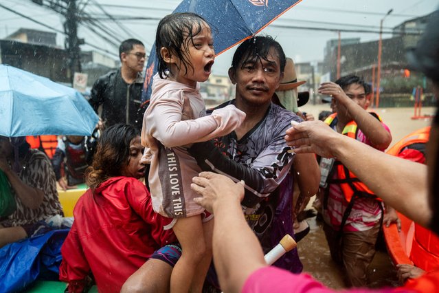 Rescuers assist a child getting off a boat along a flooded road following heavy rains brought by Typhoon Gaemi, in Marikina City, Metro Manila, Philippines, on July 24, 2024. (Photo by Lisa Marie David/Reuters)