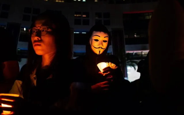 Masked students light candles during a ceremony to pay tribute to Chow Tsz-lok, 22, a university student who fell during protests at the weekend and died early on Friday morning, at the Hong Kong University of Science and Technology (HKUST) on November 08, 2019 in Hong Kong, China. Hong Kong slipped into a technical recession on Thursday after anti-government demonstrations stretched into its fifth month while protesters continue to call for Hong Kong's Chief Executive Carrie Lam to meet their remaining demands since the controversial extradition bill was withdrawn, which includes an independent inquiry into police brutality, the retraction of the word “riot” to describe the rallies, and genuine universal suffrage. (Photo by Billy H.C. Kwok/Getty Images)