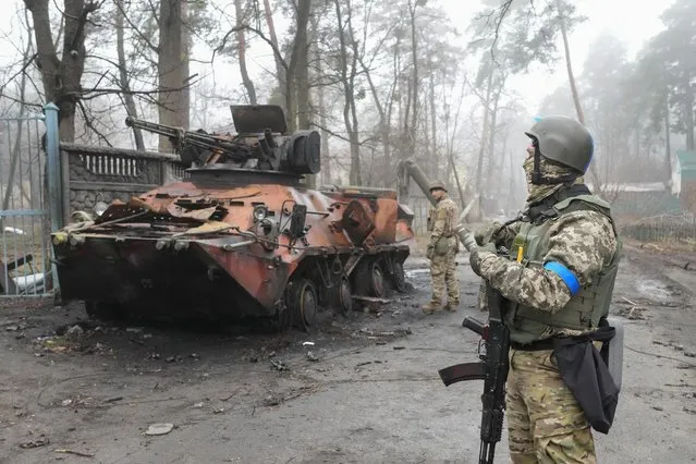 Ukrainian soldiers examine a destroyed military vehicle, in Irpin, close to Kyiv, Ukraine, Friday, April 1, 2022. Talks to stop the fighting in Ukraine resumed Friday, as another attempt to rescue civilians from the shattered and encircled city of Mariupol broke down and Russia accused the Ukrainians of a cross-border helicopter attack on an oil depot. (Photo by Efrem Lukatsky/AP Photo)
