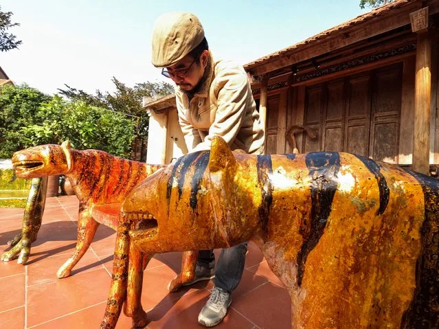Nguyen Tan Phat stands in his yard with his Tiger carving works ahead of the Lunar New year in Hanoi, Vietnam on January 18, 2022. (Photo by Reuters/Stringer)
