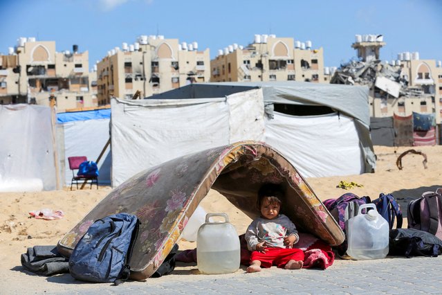 A displaced Palestinian girl sits under a mattress as waits to flee Hamad City with her family following an Israeli evacuation order, amid Israel-Hamas conflict, in Khan Younis in the southern Gaza Strip on August 11, 2024. (Photo by Hatem Khaled/Reuters)