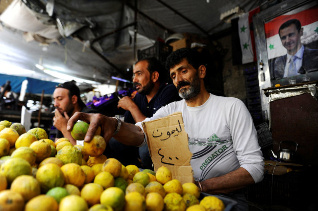 Vendors wait for customers in their stalls as people shop ahead of the Muslim fasting month of Ramadan in the old Damascus, Syria, June 5, 2016. A poster depicting Syria's President Bashar al-Assad is seen in the background. (Photo by Omar Sanadiki/Reuters)