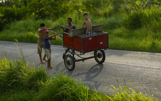 Children push a carriage in Campo Florido, east of Havana, Cuba, Monday, August 12, 2024. (Photo by Ramon Espinosa/AP Photo)