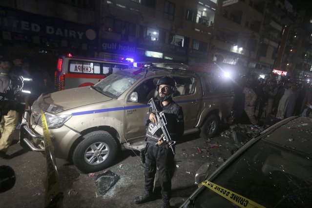 A Pakistani police officer stands next to a damaged vehicle at the site of bomb explosion, in Karachi, Pakistan, Thursday, May 12, 2022. A roadside bombing targeted a van carrying Pakistani security forces in the southern port city of Karachi on Thursday, killing and wounding few people, police said. (Photo by Fareed Khan/AP Photo)