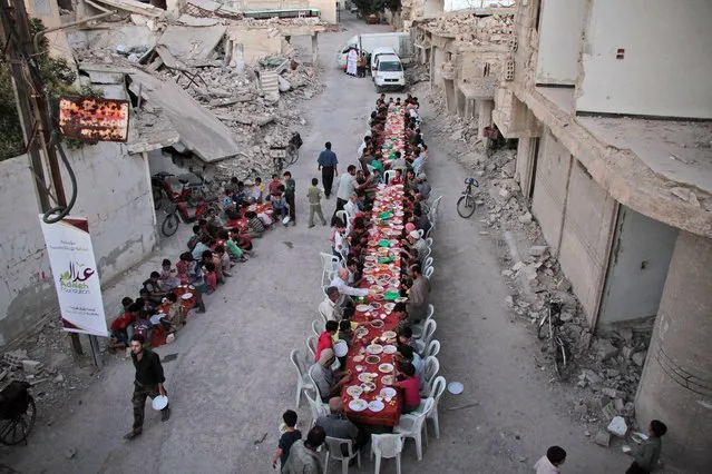 Syrian residents of the rebel-held town of Douma, on the outskirts of the capital Damascus, break their fast with the “iftar” meal on a heavily damaged street on June 18, 2017, during the Muslim holy month of Ramadan. (Photo by Hamza Al-Ajweh/AFP Photo)