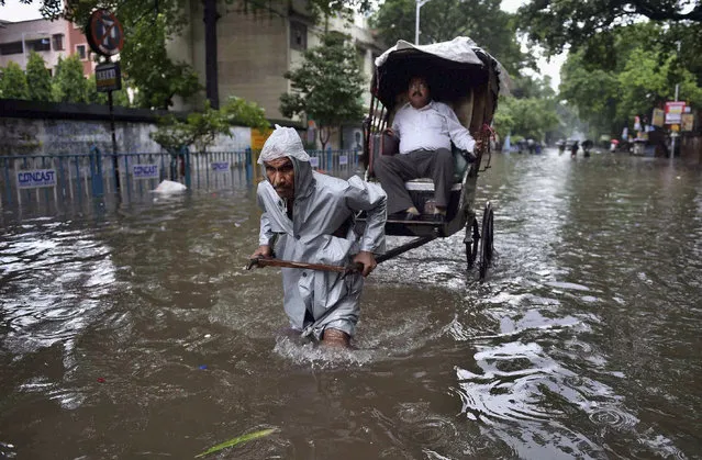 An Indian hand rickshaw puller transports a man to his destination through a water logged street after heavy rains in Kolkata, India, Saturday, August 1, 2015. Cyclonic storm Komen weakened into a depression after making landfall over Bangladesh coast on Thursday, causing heavy rainfall in several parts of the eastern Indian state of West Bengal and throwing normal life out of gear as most parts of the city were submerged, according to local reports. (Photo by Swapan Mahapatra/Press Trust of India via AP Photo)
