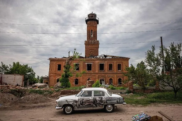 A man drives a GAZ-21 Volga car past a damaged building in Kharkiv, eastern Ukraine, on May 26, 2022, on the 92nd day of the Russian invasion of Ukraine. (Photo by Dimitar Dilkoff/AFP Photo)