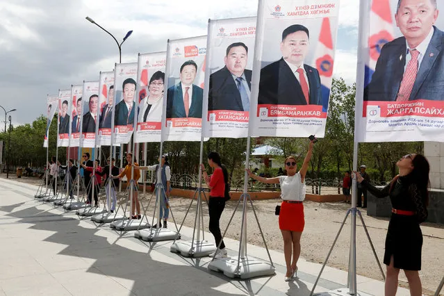 People hold flags for candidates from Mongolian People's Party for the upcoming parliamentary elections and Dornogovi Aimag's civil representatives council elections, in Dornogovi Aimag, Mongolia, June 11, 2016. (Photo by Bazarsukh Rentsendorj/Reuters)