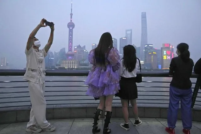 Residents enjoy the view at dusk along the bund, Wednesday, June 1, 2022, in Shanghai. Traffic, pedestrians and joggers reappeared on the streets of Shanghai on Wednesday as China's largest city began returning to normalcy amid the easing of a strict two-month COVID-19 lockdown that has drawn unusual protests over its heavy-handed implementation. (Photo by Ng Han Guan/AP Photo)