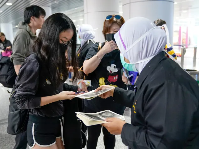 Health officials hand out information about the current coronavirus at Kuala Lumpur International Airport in Sepang, Malaysia, Tuesday, January 21, 2020. Countries both in the Asia-Pacific and elsewhere have initiated body temperature checks at airports, railway stations and along highways in hopes of catching those at risk of carrying a new coronavirus that has sickened more than 200 people in China. (Photo by Vincent Thian/AP Photo)