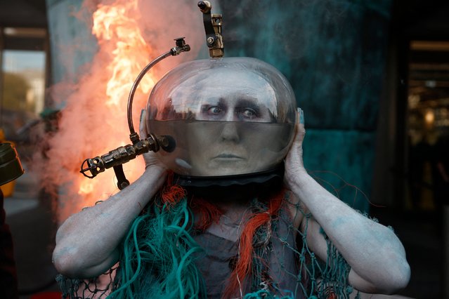 Activists from climate action group Ocean Rebellion take part in a performance using liquid natural gas beside the International Memorial to Seafarers on the Albert Embankment in London on October 4, 2024. (Photo by Benjamin Cremel/AFP Photo)