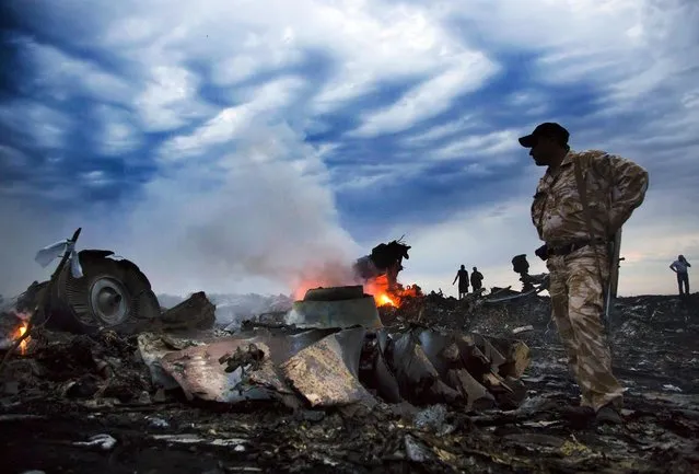People walk through debris at the crash site of a passenger plane near the village of Grabovo, Ukraine, on Jule 17, 2014.  A Ukrainian official said a passenger plane carrying 295 people was shot down Thursday as it flew over the country, and plumes of black smoke rose up near a rebel-held village in eastern Ukraine. Malaysia Airlines tweeted that it lost contact with one of its flights as it was traveling from Amsterdam to Kuala Lumpur over Ukrainian airspace. (Photo by Dmitry Lovetsky/Associated Press)