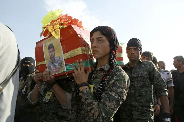Members of Syrian Democratic Forces (SDF) carry the coffin of a fellow fighter who died during an assault against the Islamic State (IS) group in the town of Manbij, during the funeral of eight SDF fighters in the Syrian Kurdish town of Kobane (aka Ain al-Arab) on June 24, 2016. The US-backed Kurdish and Arab forces pushed further into the Islamic State group stronghold of Manbij, seizing a key road junction and grain silos overlooking the city, a monitoring group said. The city lies close to the border with Turkey and is a key staging post on the jihadists' supply line to areas under its control in eastern Syria and neighbouring Iraq. (Photo by Delil Souleiman/AFP Photo)