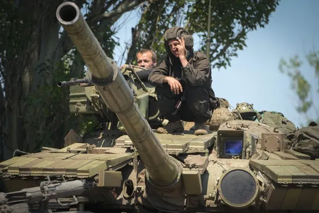 A Ukrainian soldier flashes the victory sign atop a tank in Donetsk region, Ukraine, Monday, June 20, 2022. (Photo by Efrem Lukatsky/AP Photo)