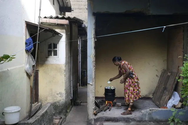 A woman cooks using a firewood hearth outside her house amid shortage of cooking gas in Colombo, Sri Lanka, Thursday, June 23, 2022. (Photo by Eranga Jayawardena/AP Photo)
