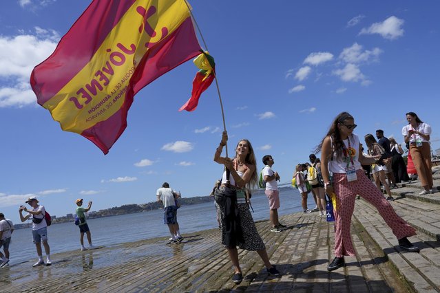 A World Youth Day pilgrim waves a Spanish flag by the water on the Tagus river bank Comercio square in Lisbon, Tuesday, August 1, 2023. Pope Francis will arrive in Portugal Aug. 2 to attend the international event that is expected to bring hundreds of thousands of young Catholic faithful to Lisbon and goes on until Aug. 6. (Photo by Ana Brigida/AP Photo)