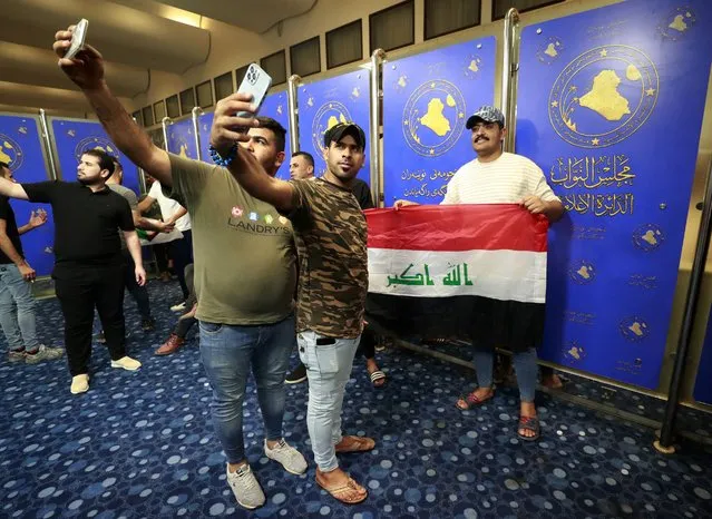 Supporters of the Iraqi cleric Moqtada Sadr take “selfie” pictures as they gather inside the Iraqi parliament in the capital Baghdad's high-security Green Zone, as they protest at a rival bloc's nomination for prime minister, on July 27, 2022. (Photo by Ahmad Al-Rubaye/AFP Photo)