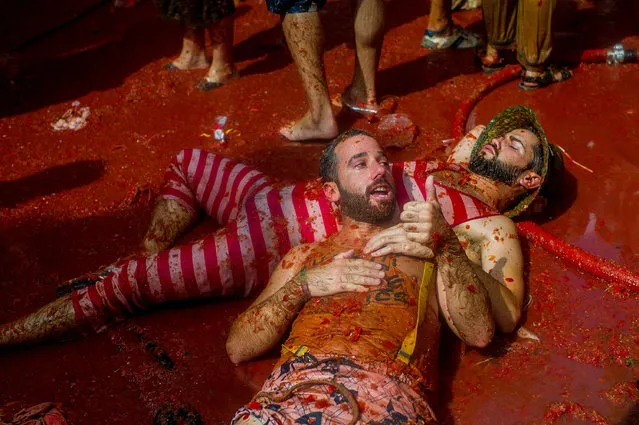 Revellers enjoy the atmosphere in tomato pulp while participating the annual Tomatina festival on August 26, 2015 in Bunol, Spain. An estimated 22,000 people threw 150 tons of ripe tomatoes in the world's biggest tomato fight held annually in this Spanish Mediterranean town.  (Photo by David Ramos/Getty Images)