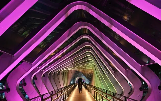 This picture taken on February 17, 2020 shows Indonesian people walking on an illuminated bridge in Jakarta. (Photo by Adek Berry/AFP Photo)