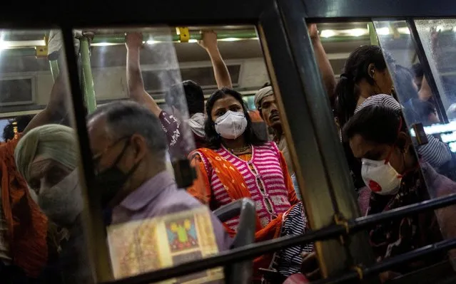 Commuters wearing protective masks as a precaution against the spread of coronavirus disease (COVID-19), travel in a crowded bus during evening rush hour, in New Delhi, India, March 18, 2020. (Photo by Danish Siddiqui/Reuters)