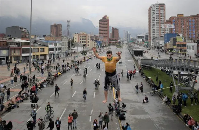 An acrobat performs during a protest against the government of Colombian President Ivan Duque to mark the first anniversary of a social outbreak, outside the Nacional University in Bogota, on April 28, 2022. Colombia was rocked by weeks of protests last year following opposition to a proposed tax hike that morphed into a mass movement against the right-wing administration of President Ivan Duque. At least 60 people died. (Photo by Raul Arboleda/AFP Photo)