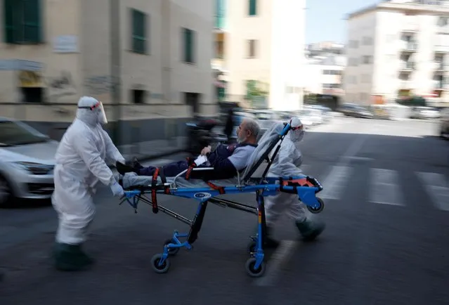 Medical staff in full protective gear carry a patient on a stretcher down a street in Naples, as the spread of coronavirus disease (COVID-19) continues, Italy, April 2, 2020. (Photo by Ciro De Luca/Reuters)