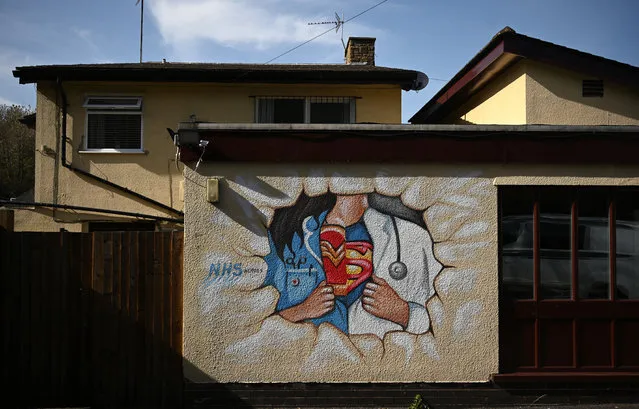 A picture shows graffiti depicting the badge of a superhero under a nurse's and doctor's uniform in homage to the efforts of NHS staff during the coronavirus crisis on a wall in Pontefract, northern England on April 14, 2020, as life in Britain continues during the nationwide lockdown to combat the novel coronavirus pandemic. The British government warned Monday it would not be lifting a nationwide lockdown anytime soon as the country remains in the grip of a coronavirus outbreak that has claimed more than 11,000 lives. (Photo by Oli Scarff/AFP Photo)