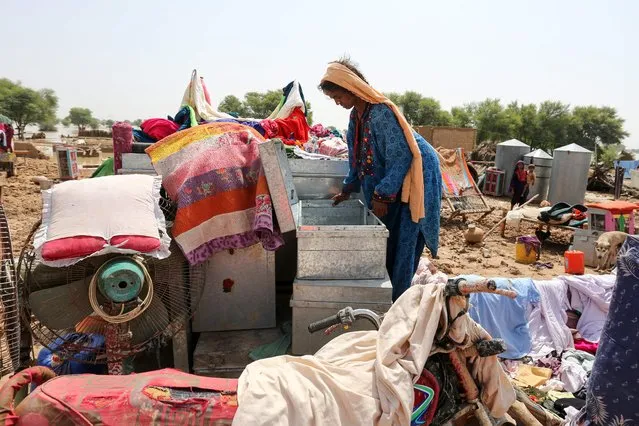 A flood affected woman goes through her belongings next to her damaged mud house following heavy monsoon rains in Rajanpur district of Punjab province on August 27, 2022. Heavy rain pounded much of Pakistan on August 26 after the government declared an emergency to deal with monsoon flooding it said had affected more than 30 million people. (Photo by Shahid Saeed Mirza/AFP Photo)