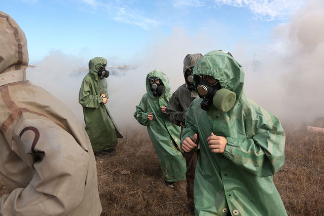 Schoolchildren wearing gas masks and suits attend a training in the military-patriotic program “School of Future Commanders” in Sevastopol on October 28, 2023. The training conducted under the guidance of military personnel include disciplines such as multi-sport racing, tactical medicine, and weapons handling. (Photo by AFP Photo/Stringer)