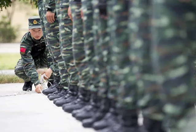 A soldier of China's People's Liberation Army uses a rope to line up other soldiers during a training session for a military parade to mark the 70th anniversary of the end of World War Two, at a military base in Beijing, China, September 1, 2015. (Photo by Reuters/Stringer)