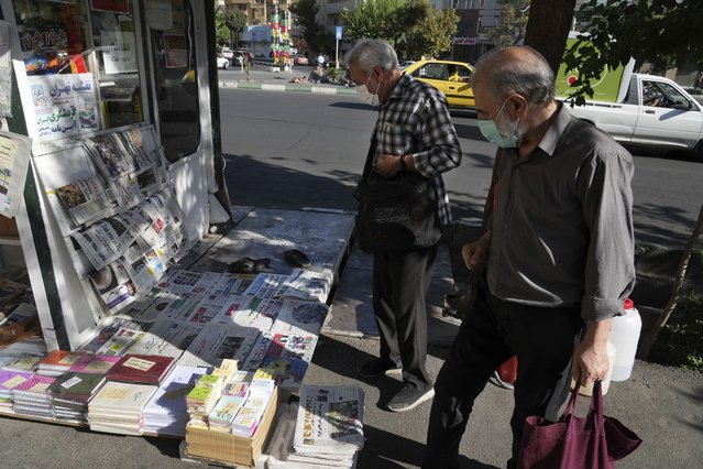 People scan publications at a news stand in Tehran, Iran, Saturday, August 13, 2022. Salman Rushdie, whose novel “The Satanic Verses” drew death threats from Iran’s leader in the 1980s, was stabbed in the neck and abdomen Friday by a man who rushed the stage as the author was about to give a lecture in western New York. (Photo by Vahid Salemi/AP Photo)