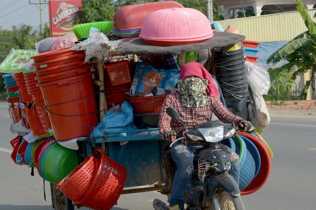 A Cambodian man rides his motor-cart loaded with goods along a street on the outskirts Phnom Penh, Cambodia on October 30, 2017. (Photo by Tang Chhin Sothy/AFP Photo)