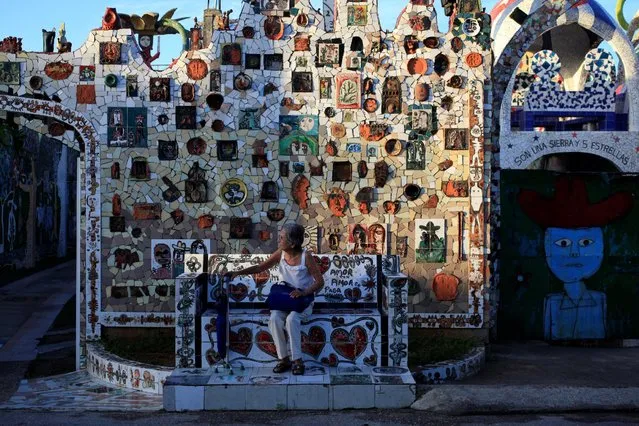 An old woman sits near a wall decorated with mosaics of Cuban artist Jose Fuster in the seaside village of Jaimanitas in Havana, Cuba, July 14, 2016. Fuster has also adorned the facades of houses in the neighborhood with Picasso-like paintings and playful ceramic figures, transforming the humble neighborhood into an island of brightness. (Photo by Enrique de la Osa/Reuters)