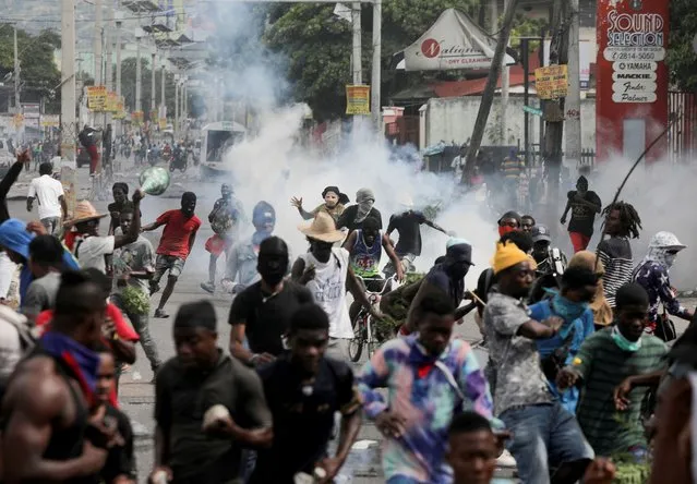 People run while police fire tear gas during a protest demanding the resignation of Haiti's Prime Minister Ariel Henry after weeks of shortages, in Port-au-Prince, Haiti on October 10, 2022. (Photo by Ralph Tedy Erol/Reuters)