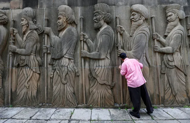 A Parsi man touches the walls of a Parsi fire temple featuring huge carvings of ancient priests during the Parsi New Year day in Mumbai, India, August 17, 2016. (Photo by Danish Siddiqui/Reuters)