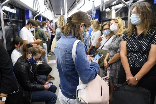 People wearing protective mask ride the “Transports publics lausannois”, TL, Metro M2 (underground) during the coronavirus disease (COVID-19) outbreak, in Lausanne, Switzerland, Monday, July 6, 2020. In Switzerland, from Monday 6 July, people aged 12 and over must wear a mask in all public transport, trains, trams and buses, as well as in cable cars and boats. (Photo by Laurent Gillieron/Keystone via AP Photo)