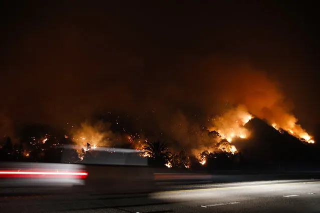 Traffic moves along the Highway 33 as a wildfires continues to burn Tuesday, December 5, 2017, near Oak View, Calif. Raked by ferocious Santa Ana winds, explosive wildfires northwest of Los Angeles and in the city's foothills burned a psychiatric hospital and scores of homes and other structures Tuesday and forced the evacuation of tens of thousands of people. (Photo by Jae C. Hong/AP Photo)
