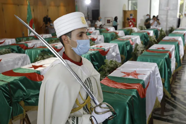 A soldier guards the remains of 24 Algerians at the Moufdi-Zakaria culture palace in Algiers, Friday, July, 3, 2020. After decades in a French museum, the skulls of 24 Algerians decapitated for resisting French colonial forces were formally repatriated to Algeria in an elaborate ceremony led by the teary-eyed Algerian president. The return of the skulls was the result of years of efforts by Algerian historians, and comes amid a growing global reckoning with the legacy of colonialism. (Photo by Toufik Doudou/AP Photo)