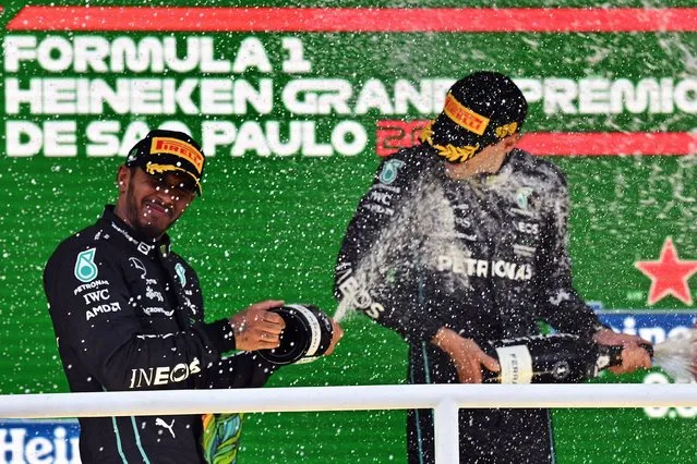 Second placed Mercedes' British driver Lewis Hamilton (L) and winner Mercedes' British driver George Russell celebrate with champagne in the podium of the Formula One Brazil Grand Prix, at the Autodromo Jose Carlos Pace racetrack, also known as Interlagos, in Sao Paulo, Brazil, on November 13, 2022. (Photo by Nelson Almeida/AFP Photo)