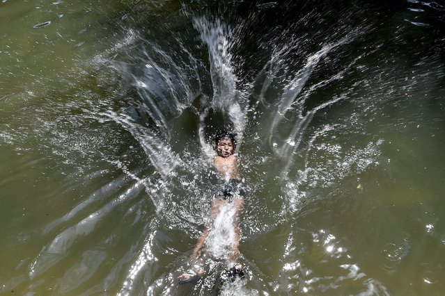 A boy jumps in a water canal to cool himself off on a hot summer day in Jalandhar on April 25, 2025. (Photo by Shammi Mehra/AFP Photo)