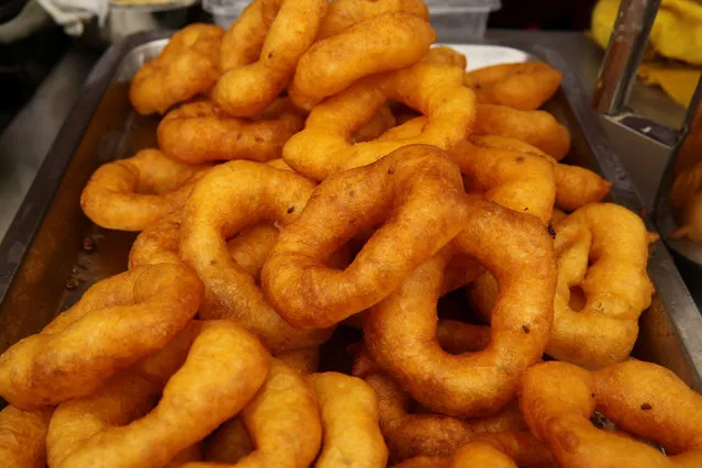Cook serve traditional dessert “Picarones” during Mistura gastronomic fair, which promotes Peruvian cuisine by showcasing food and products from all over the country, in Lima, Peru, September 8, 2016. Picarones is a Peruvian dessert that originated in Lima during the viceroyalty. It is somewhat similar to buñuelos, a type of doughnut brought to the colonies by Spanish conquistadors. Its principal ingredients are squash and sweet potato. It is served in a doughnut form and covered with syrup, made from chancaca (solidified molasses). It is traditional to serve picarones when people prepare anticuchos, another traditional Peruvian dish. (Photo by Mariana Bazo/Reuters)