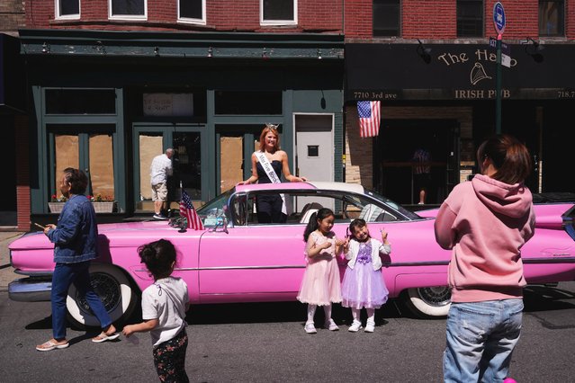 A person takes photographs of children standing next to a car with Miss Five Boroughs 2025, Cassie Donegan, at the 158th Memorial Day Parade, in Brooklyn, New York City, on May 26, 2025. (Photo by Adam Gray/Reuters)