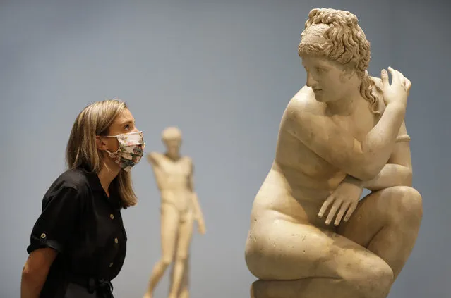 A museum employee looks towards a marble statue of Crouching Venus, Roman, 2nd century AD, during a press view at The British Museum in London, Monday, August 24, 2020. The museum will reopen to the public on Aug. 27. A new one-way route round the Ground Floor galleries will allow visitors access to many thousands of objects. (Photo by Kirsty Wigglesworth/AP Photo)