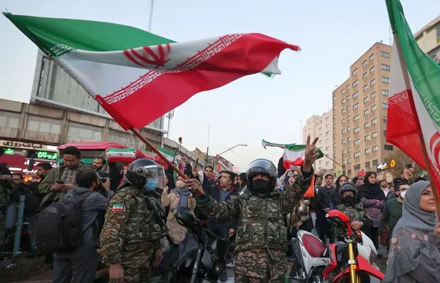 A member of Iran's riot police waves a national flag as fans celebrate their football team's win against Wales during the Qatar 2022 World Cup, in the capital Tehran on November 25, 2022. Iran struck twice in the dying moments of added time to earn a 2-0 win over 10-man Wales in their Group B clash at the World Cup today. Rouzbeh Cheshmi and Ramin Rezaeian scored to give Iran a famous win, which moved them into second place in the group behind England, who face the USA later in the day. (Photo by Atta Kenare/AFP Photo)