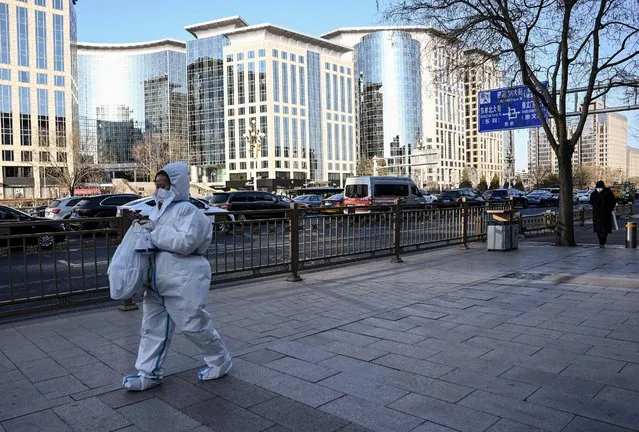 A woman wearing personal protective equipment (PPE) amid the Covid-19 pandemic walks along a street in Beijing on December 26, 2022. (Photo by Noel Celis/AFP Photo)